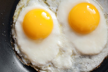 Macro photo of two scrambled eggs in black frying pan