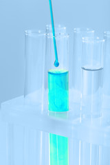 Test-tubes with blue liquid and stick on blue background