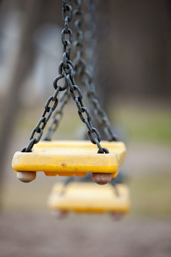 Empty Yellow Plastic Swings On A Playground