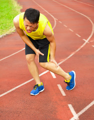 Obraz premium young male runner suffering from leg cramp on the track