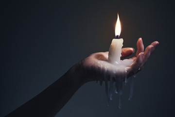 Holding a candle on a dark background.