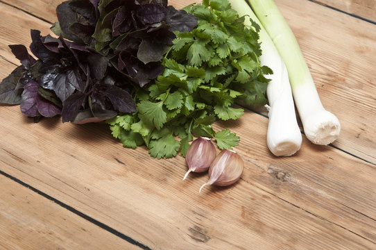 food background on  wooden table: parsley, basil, garlic, and le