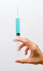 Blue vaccine in syringes on right hand.