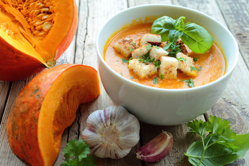 Pumpkin soup in a bowl with fresh herbs