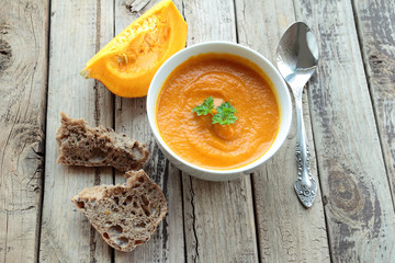 Pumpkin cream soup in a bowl on a wooden table