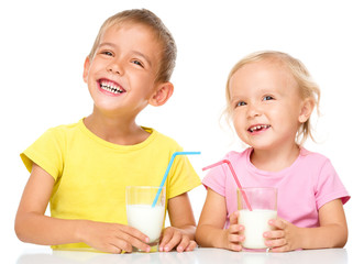 Fototapeta premium Cute little girl and boy are drinking milk