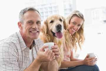 Smiling casual couple sitting on couch having coffee