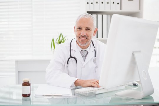 Happy doctor typing on keyboard