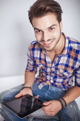 fashion man holding a tablet pad computer while smiling