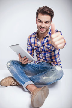 fashion man sitting andz showing thumbs up gesture