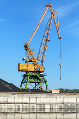 Big industrial harbor crane stands on the river coast in port
