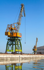 Fototapeta na wymiar Big industrial harbor cranes works on the river coast
