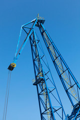 Upper part of big industrial port crane above blue sky