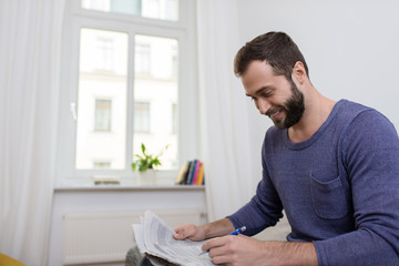 lächelnder mann liest anzeigen in tageszeitung