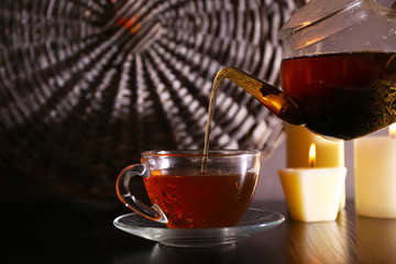 Tea pouring into glass cup on dark background