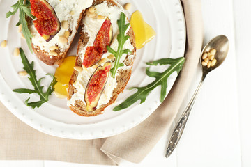 Tasty sandwiches with sweet figs and cottage cheese on plate