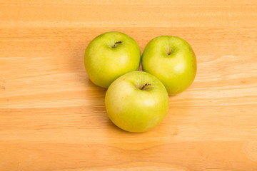 Three Granny Smith Apples on Wood Counter