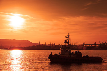 Tug is underway on Black sea at sunset, Varna harbor, Bulgaria