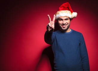Smiling young santa showing the victory sign