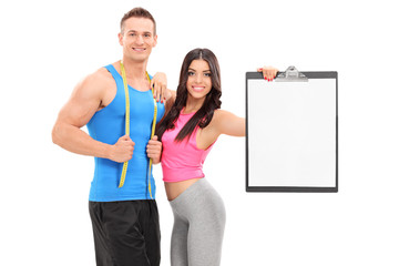 Man and woman in sportswear posing with a clipboard