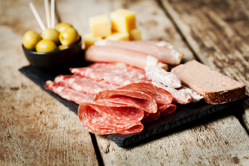Charcuterie assortment and olives on wooden background