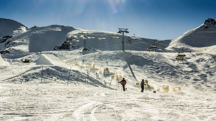 Beautiful snowy landscape with machines for skiing slope prepara