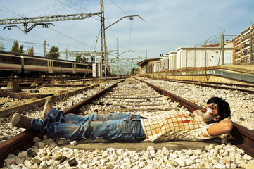 scary zombie taking a nap at abandoned railroad tracks