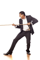 African businessman pulling a rope on white background