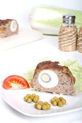 meatloaf with egg tomato and green peas on a white background