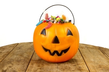 A plastic pumpkin filled with candy wooden table