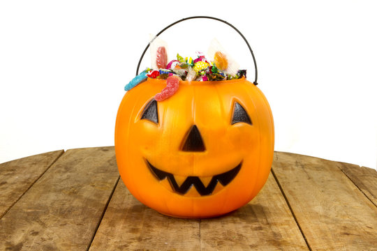 A Plastic Pumpkin Filled With Candy Wooden Table