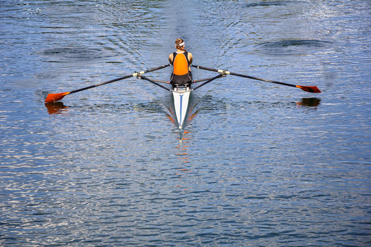 The woman rower in a boat, rowing on the tranquil lake 