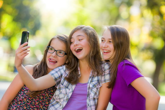 Happy teen girls taking selfie in park - Powered by Adobe
