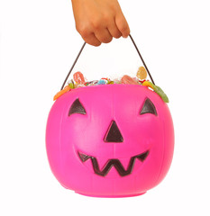 Kid holding a pink plastic pumpkin filled with candy