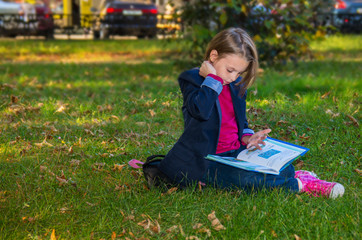 Pretty girl of school age in the autumn park.