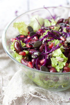 mixed salad on glass bowl with red beans, seeds, purple cabbage