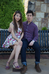 Asian couple sitting together on an iron bench