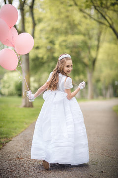 ni&ntilde;a corriendo por la calle con globos