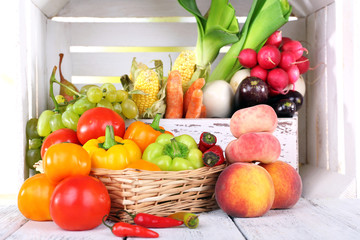Vegetables in crate and in basket on white wooden box