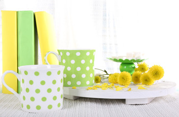 Two cups of tea and books on table on curtain background
