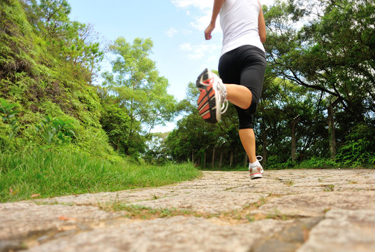 fitness woman runner legs running on stone trail