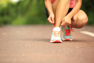 woman runner tying shoelace on  trail