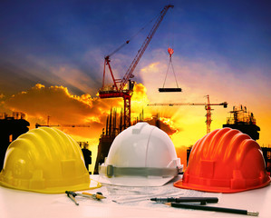 Fototapeta na wymiar safety helmet on civil engineer working table against crane lift