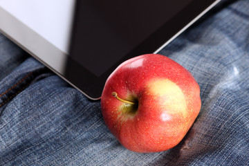 Apple and digital tablet on jeans