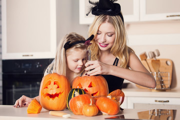 Kid on Halloween party making carved pumpkin with a little help 