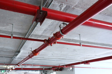 red pipeline extinguishing water in industrial building - obrazy, fototapety, plakaty