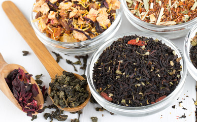 assortment of dry tea in glass bowls on wooden surface