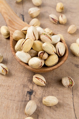 full spoon bowl of pistachio on wooden surface