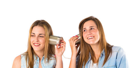 Friends talking through a tin phone over white background