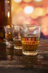 glass of rum whiskey over defocused lights background